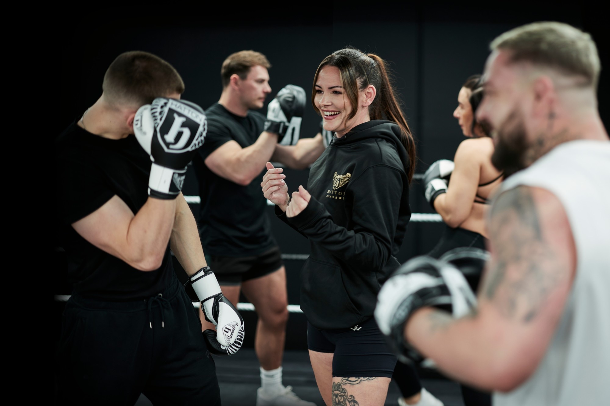 Smiling Hatton Boxing instructor leading a padwork class in the ring