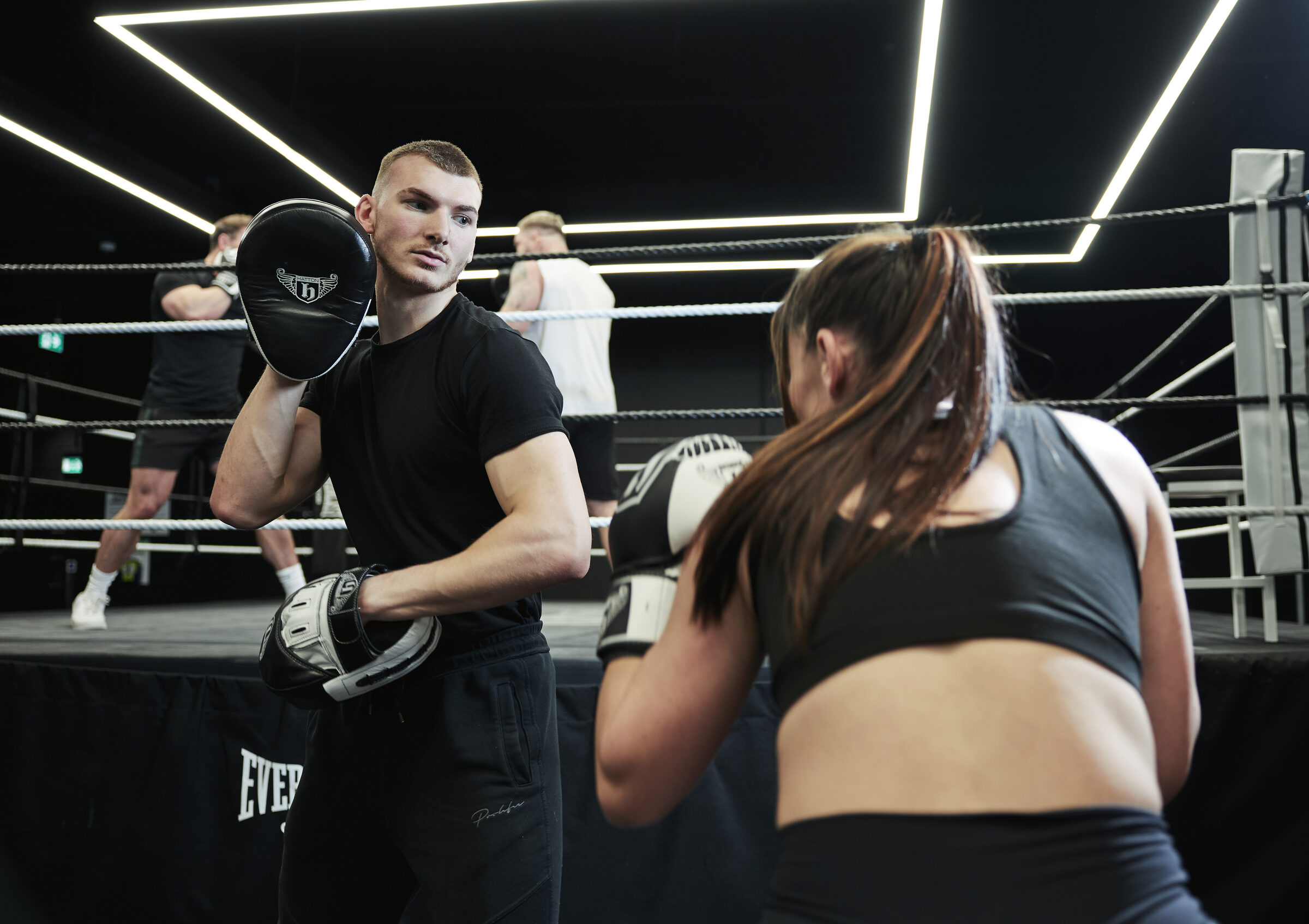 Hatton Boxing instructor holding pads for a client wearing gloves in the ring