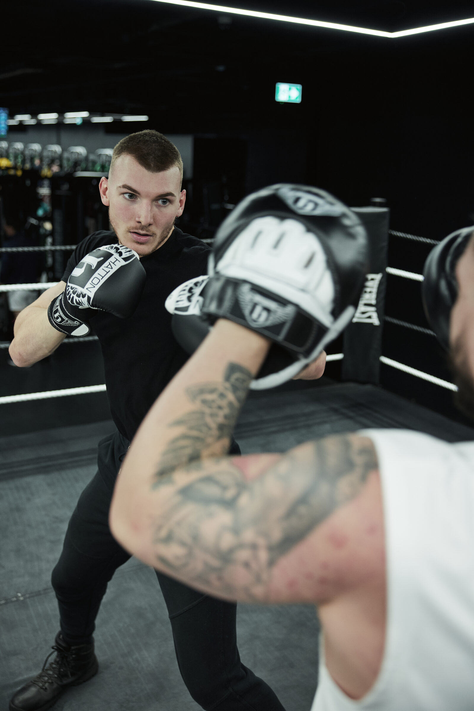 Two people working on pads and gloves in the ring